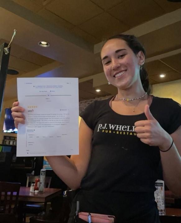 Rowan student and waitress Madison Miller stands with her five-star Yelp review. - Photo / Lilly Frankel 