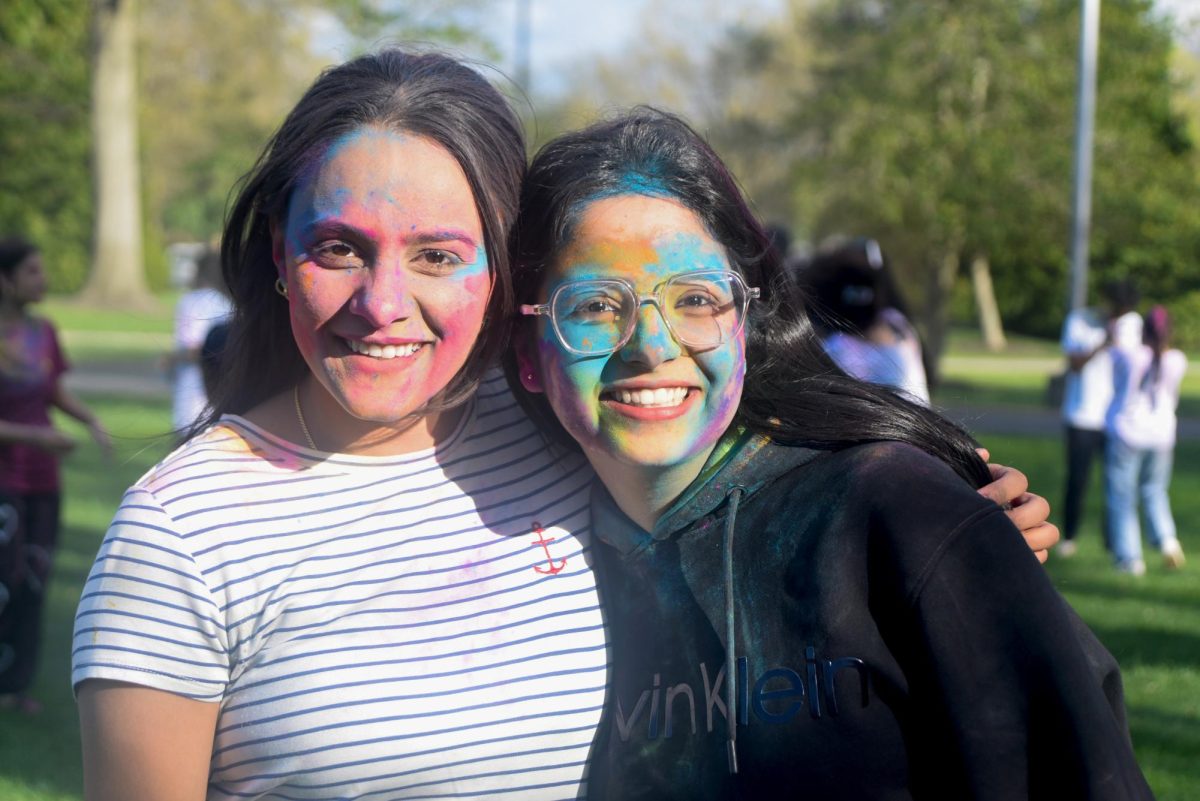 Sophomore Jaspreed Kaur and freshman Paulak Raswand pose while covered in gulal at the annual Holi celebration. April 15, 2025. - Staff Writer / Kacie Scibilia